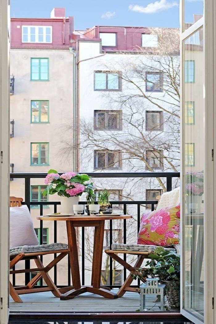 decoration balcon, bouquet de fleurs rose, tables ronde, chaises en bois, coussins décoratifs