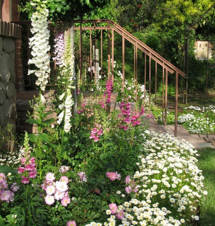 bordure parterre de fleurs conte le mur extérieur d'une maison, fleurs blanches et roses, aménagement jardin maison rustique