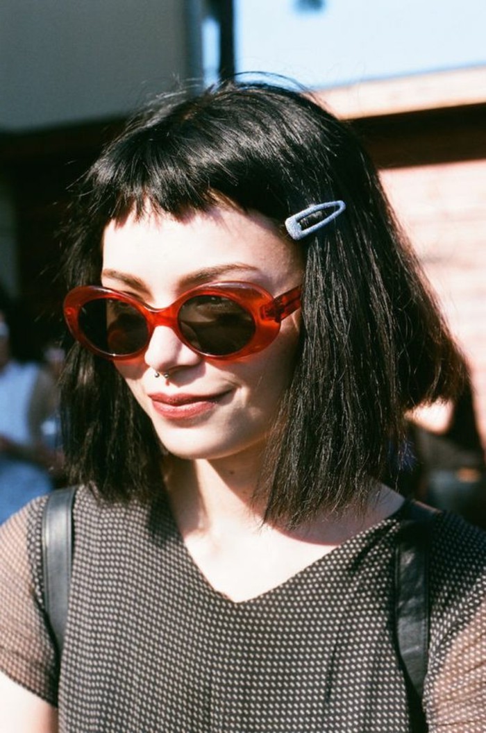 coiffure femme frange, carré cheveux couleur noir et lunettes de soleil rouges 