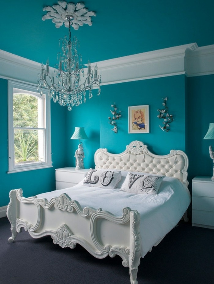 chambre turquoise, lustre en cristaux, tête de lit en cuir et bois, tapis foncé