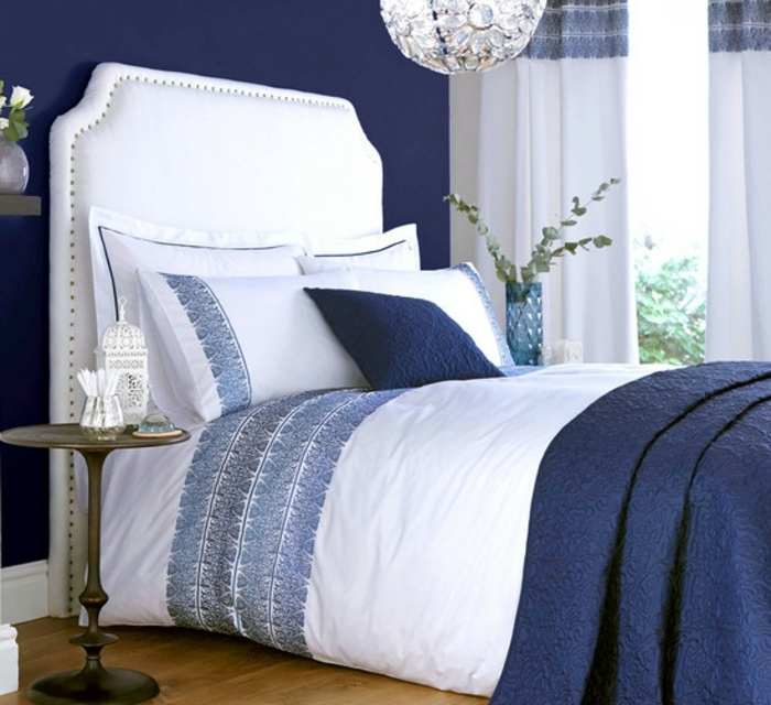 deco-chambre-adulte-bleu-couverture-de-lit-et-peinture-murale-bleu-indigo-tete-de-lit-capitonée-blanche-linge-maison-et-rideaux-blancs-a-motifs-floraux-bleus