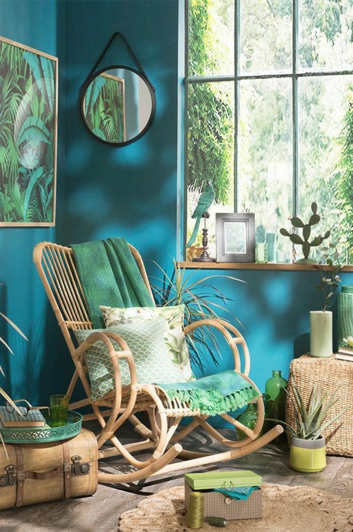 chambre turquoise, miroir rond noir, chaise à basculer, parquet en bois, grande fenêtre, jungle