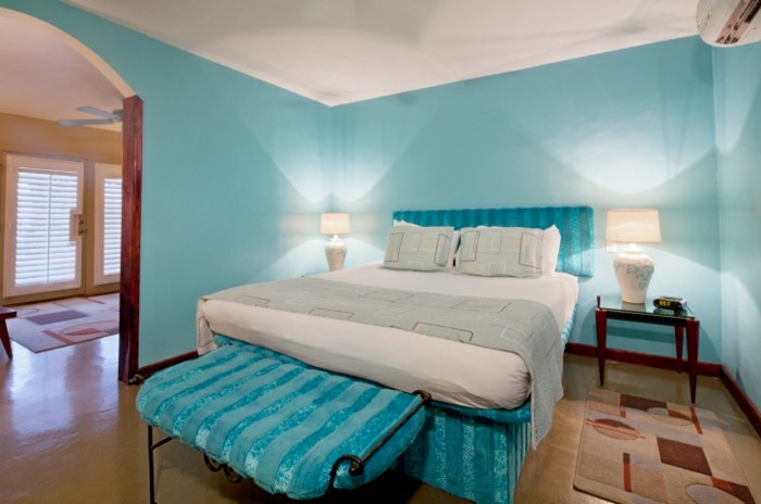 chambre turquoise, lampe de chevet blanche, plafond blanc, tapis marron et beige