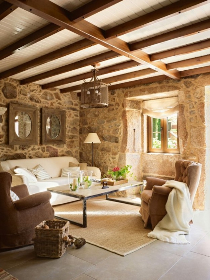 salon cocooning, plafond avec poutres en bois, tapis beige, canapé blanc, miroir rond, fauteuil marron