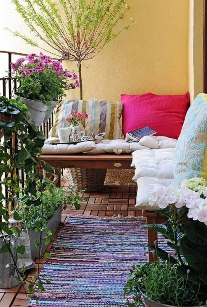idee deco terrasse, sol en bois, petit banc, coussins colorés, plantes vertes, livre, petit déjeuner