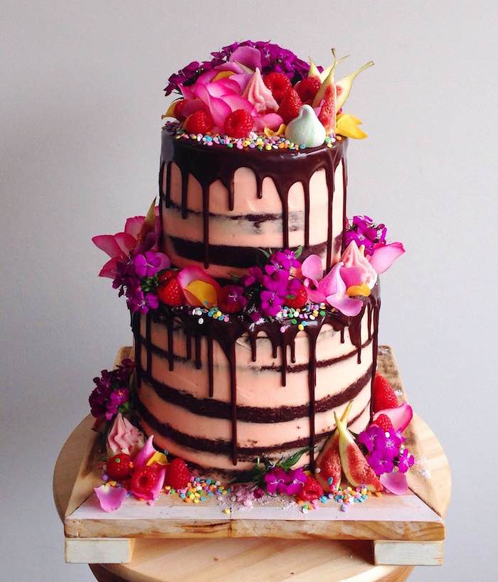 glaçage chocolat pour décorer un gateau au chocolat anniversaire avec creme rose, decoration de fleurs fraiches, billes colorées, meringues et fruits