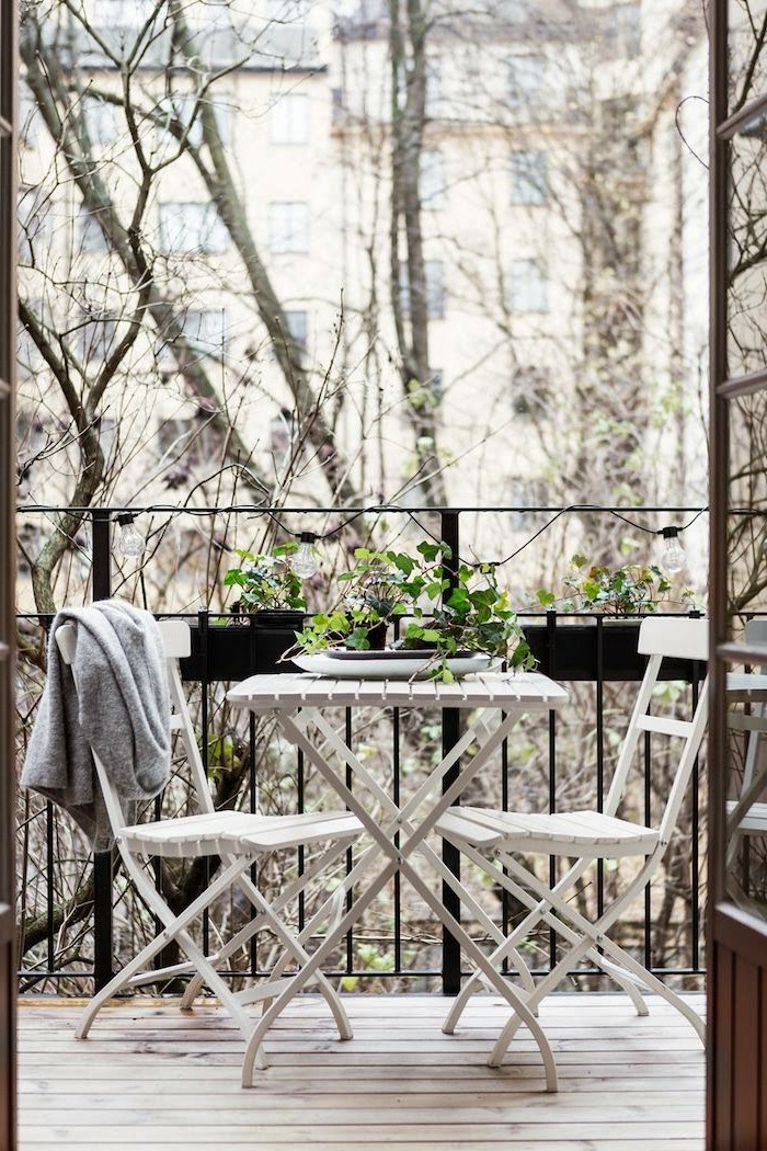 aménager son balcon, sol en bois, véranda en fer forgé, fleurs vertes, chaise blanche, gilet gris