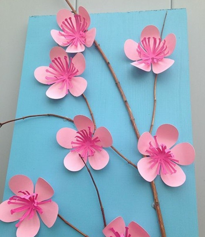 activité manuelle printemps maternelle, une branche d'arbre décorée de petites fleurs rose en papier, petits enfants bricolage