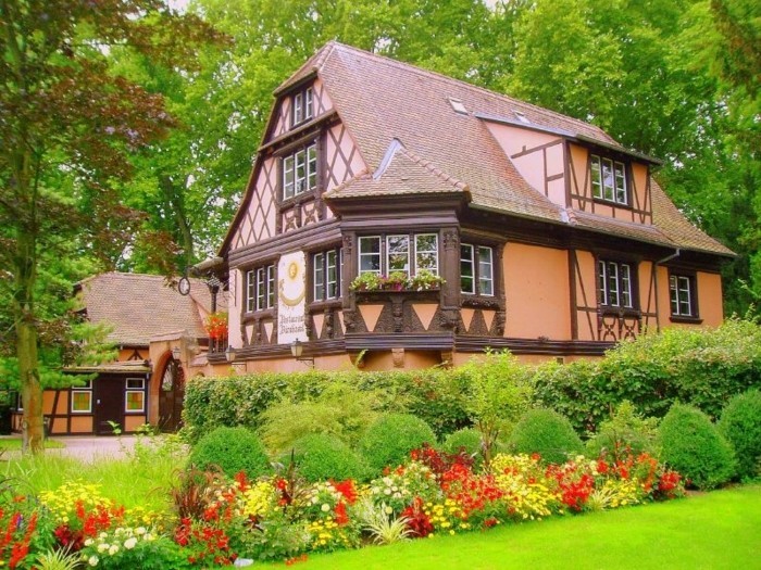 maison à colombage vintage, buis, arbustes et parterre de fleurs champêtres de couleurs diverses, paysage pastoral