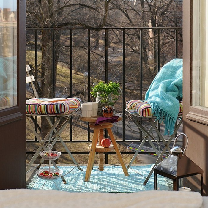 decoration balcon, tapis turquoise, couverture à franges, table ronde en bois, tasses de café