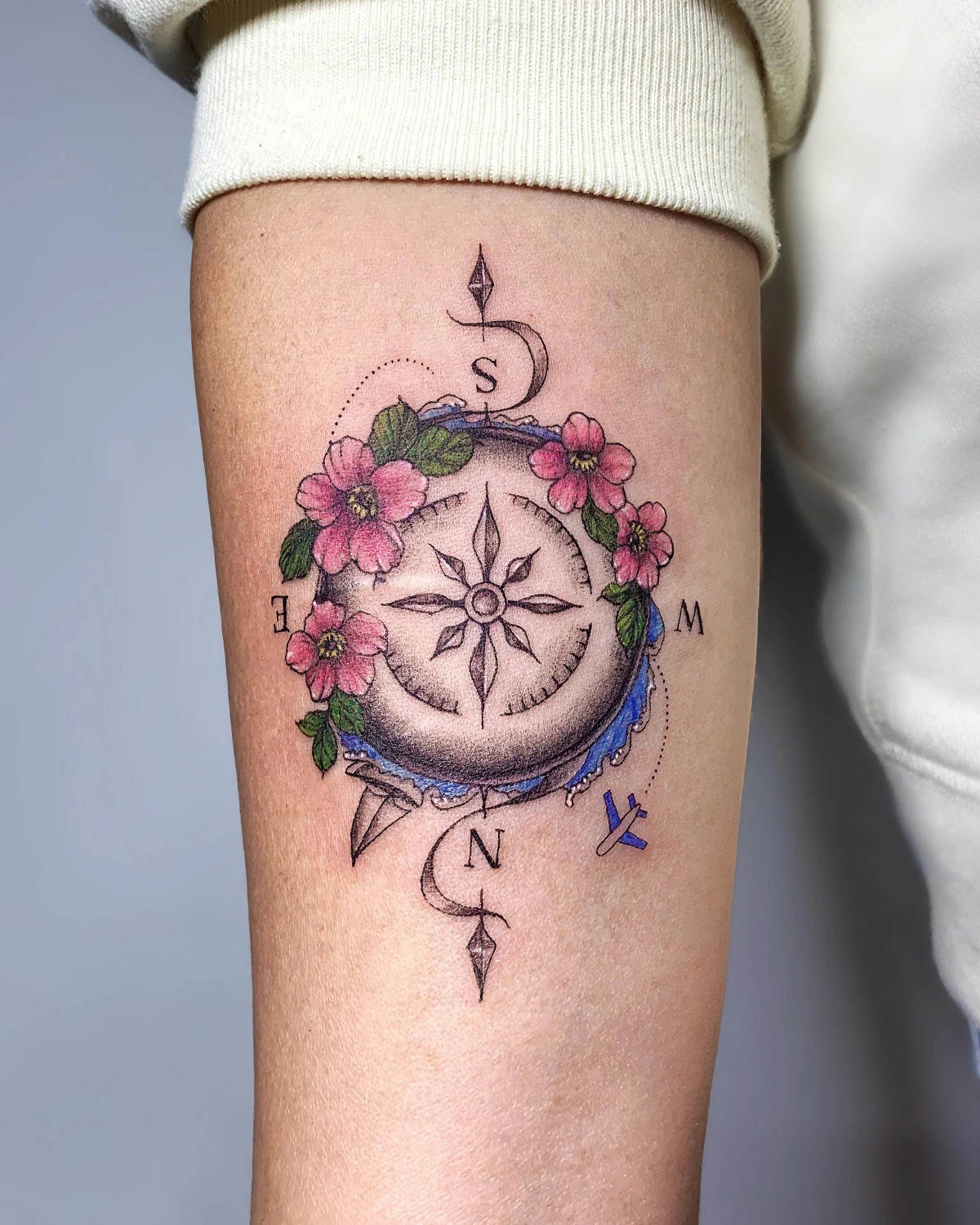 tatouage boussole du voyageur couleurs fleurs bras femme