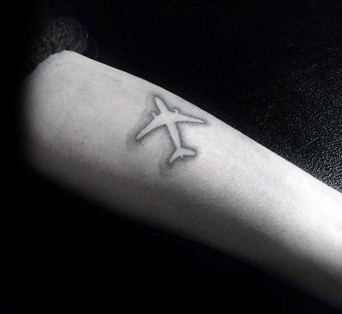 arbre du voyageur tatouage avion en négatif sur bras homme