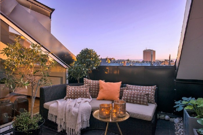 terrasse tropezienne style zen oriental, petite table en cuivre, canapé noir, plaid, plantes, carrelage noir, idée deco terrasse 