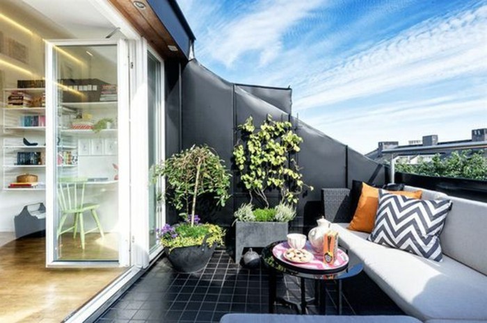 table basse noire, carrelage noir, canapé noi, coussin d'assise gris, plantes, idée tropezienne terrasse, vue sur la ville