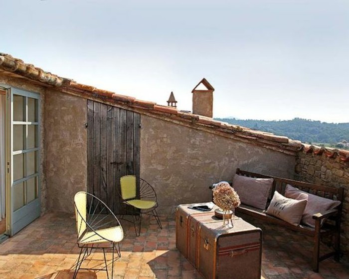 tropezienne terrasse style méditerranéen, chaises en métal, malle vintage en guise de table basse, banc en bois, coussins