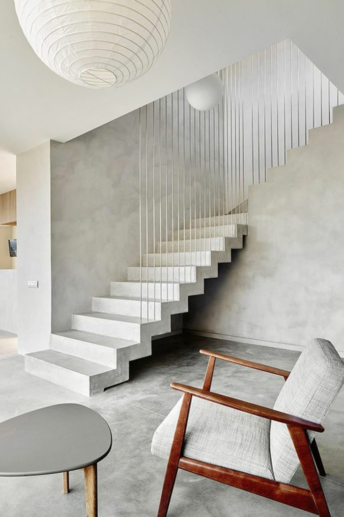 appartement minimaliste, fauteuil en bois et tissu, escalier moderne, murs et sol et béton ciré