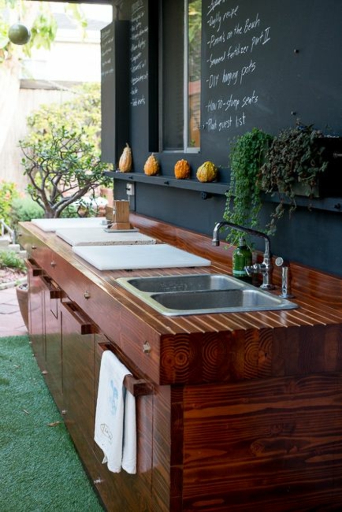 une cuisine d'extérieur en bois compact et mur en ardoise