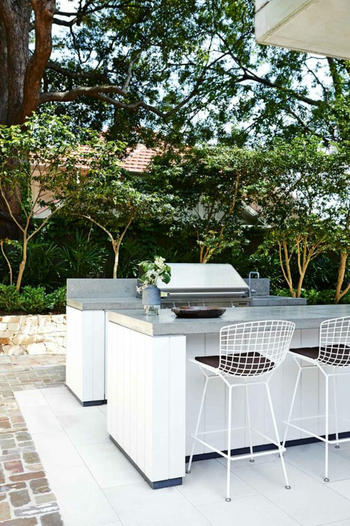 espace barbecue et cuisine d'extérieur au design épuré et élégant en blanc, des tabourets de bar métalliques