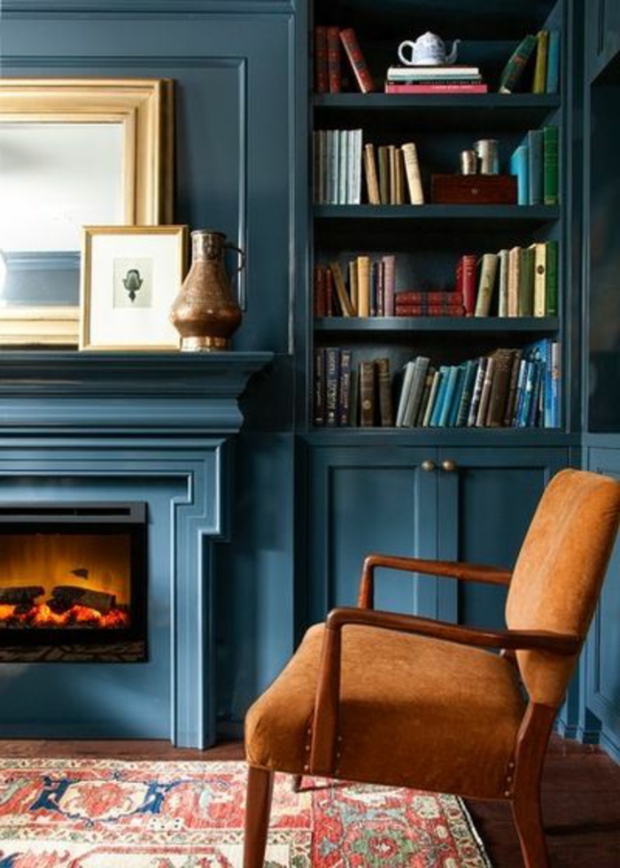 deco salon bleu canard, bibliothèque bleue avec cheminée murale, fauteuil couleur ocre 