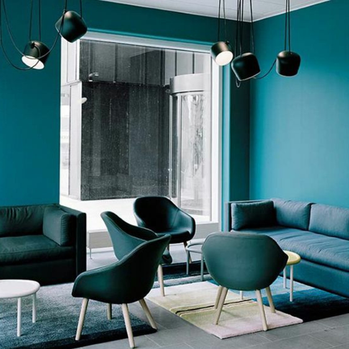 mur bleu canard, chaises bleues, sofas bleus rectangulaires, lampes style industriel