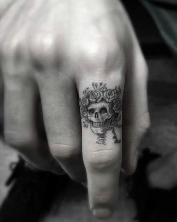 un tatouage doigt homme à tête de mort et roses, un joli dessin à encre graphique