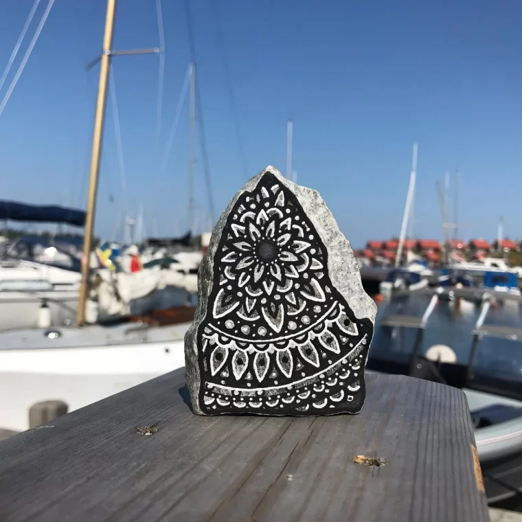 dessin mandala noir et blanc sur pierre vue bateaux ciel bleu