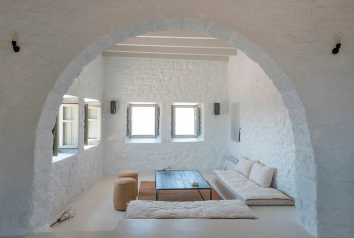 meuble en pierre grec, murs blanchis à la chaux, volets kaki, table basse en bois