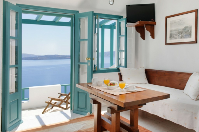 repas grec, volets en turquoise, vue sur la mer, canapé et table en bois