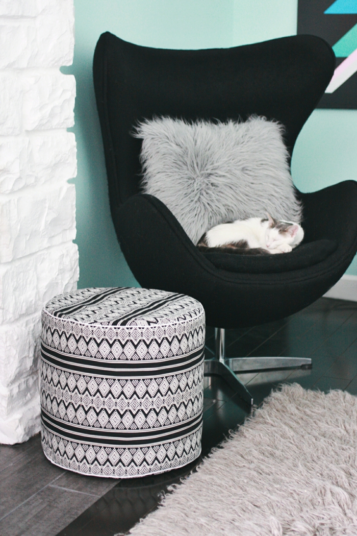 pouffe geant, tapis moelleux, fauteuil noir, coussin en fausse fourrure, mur turquoise