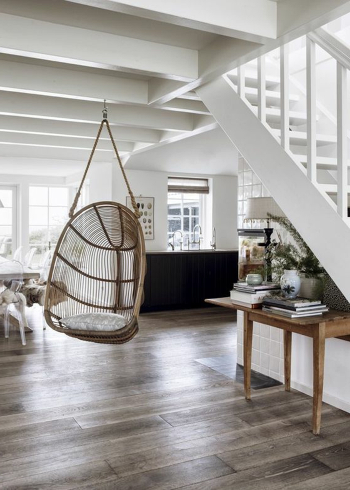 fauteuil balancelle, maison blanche avec escalier blanc et table en bois sous l'escalier 