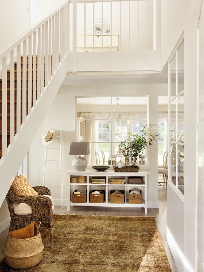 idée home staging, échelle décorative en bois, lampe en gris, fauteuil en rotin, entrée ouverte en blanche