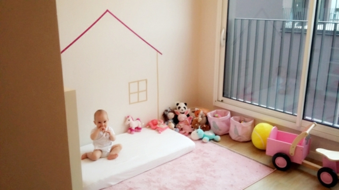 méthode montessori amenagement, matelas blanc, tapis rose, jouets, bacs à jouets, mur couleur ivoire, dessin mur maison