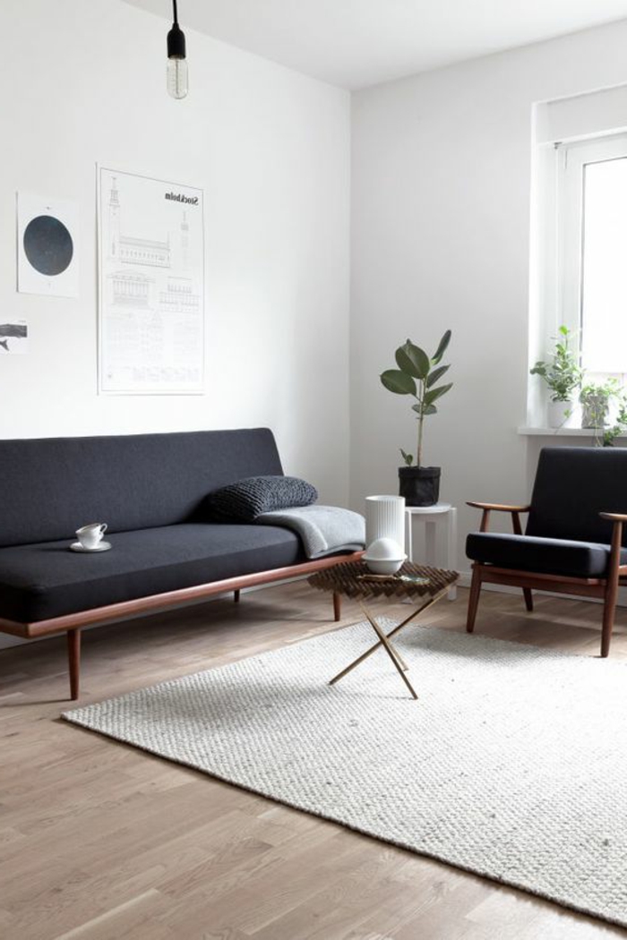 intérieur minimaliste, sofa noir style mid century, murs blancs, tapis gris clair