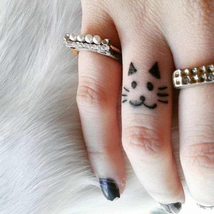 un adorable tatouage sur le doigt à motif chat, dessin simple et 