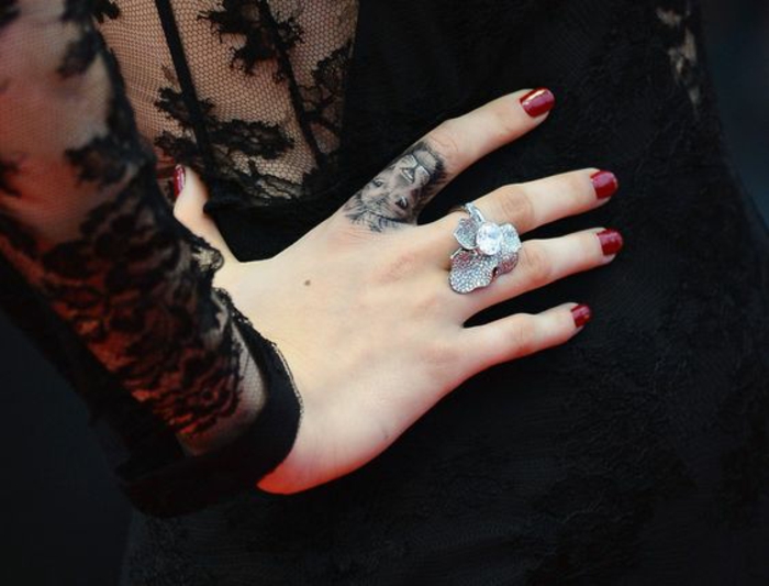 un tatouage main original réalisé sur le doigt, tatouage lion qui fait office de bague
