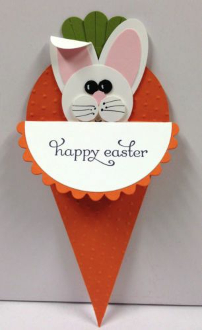 joyeuses-paques-carotte-lapin-de-paques-carte-de-voeux-originale-en-forme-de-carotte-activité-manuelle-paques lapin de paques blanc, des oreilles rose, dans une carotte en papier orange, idée originale de carte joyeuses paques, activité manuelle printemps