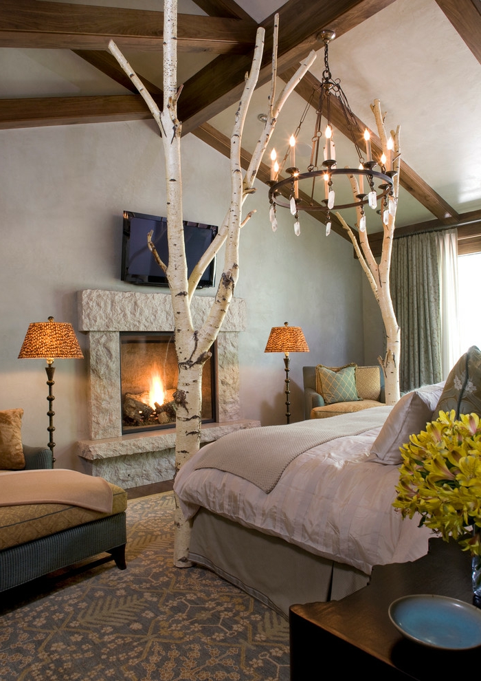lit douillet, cheminée en pierre, grand lit, coussins décoratifs, fauteuil beige, lustre à bougies