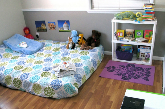 lit bébé matelas à motifs floraux, parquet, rangement livres, jouets, deco murale photo, curiosités, couleur mur en gris et blanc