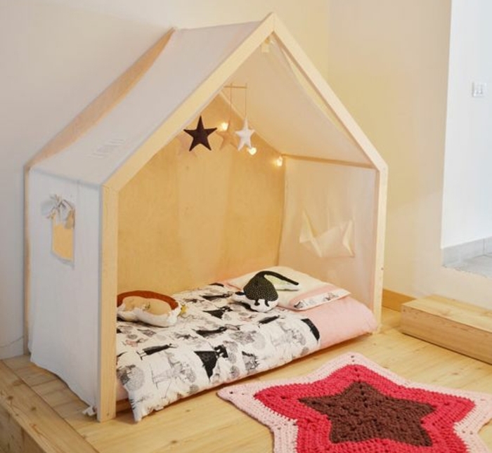 mur couleur blanche, maisonnette en bois, voiles, matelas, couverture de lit noir et blanc, tapis tricot en forme d étoile, parquet clair