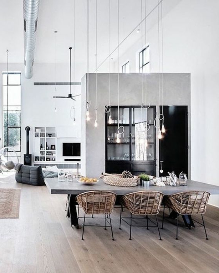 maison minimaliste, grande table en béton ciré, chaises tressées, ampoules pendantes