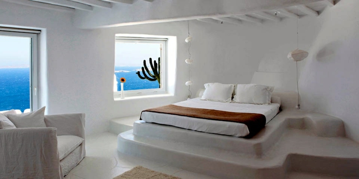 décoration grecque, murs blancs, plafond avec poutres en bois, lit surélevé, vue sur la mer