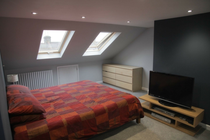 couleur mur gris, linge de lit rouge et marron, meuble TV, commode en bois, mur d accent gris anthracite, tapis beige, amenagement comble