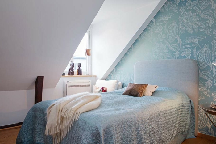 mur d accent, papier peint bleu à motifs floraux, lit gris, couverture de lit bleue, parquet clair, couleur mur blanc, déco chambre sous pente