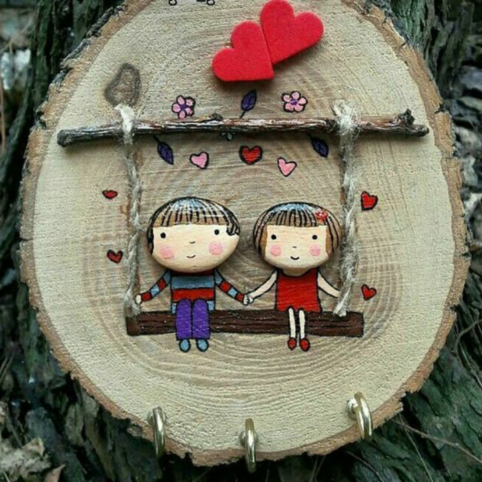 peindre des galets, un berceau avec deux enfants en galets sur un rondin de bois
