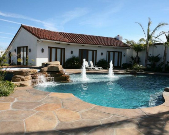jolie piscine avec faux rochers et cascade, contour piscine en béton décoratif effet pierre