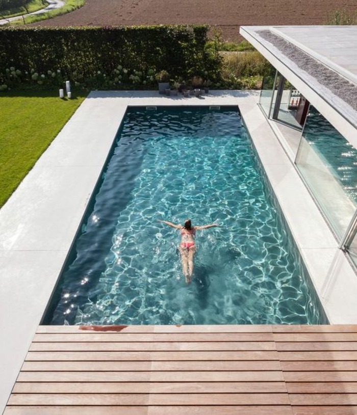 une plage de piscine bois composite, un couloir de nage aux abords en béton