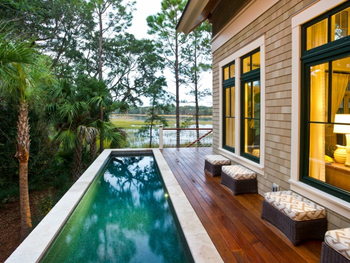 piscine surélevée, tabourets marron, grandes fenêtres, palmier tropical, clôture en bois