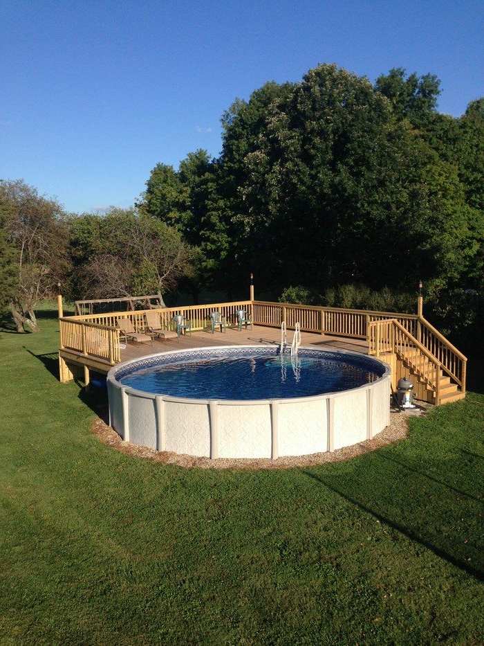 piscine surélevée en forme ronde, terrasse de piscine en bois, jardin en gazon