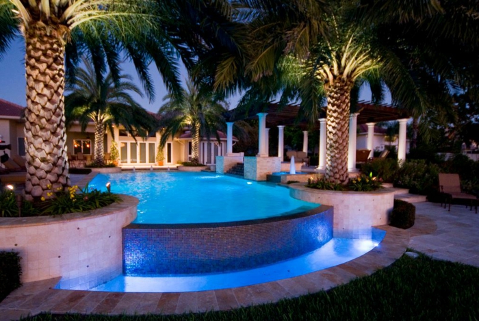 piscine hors sol rectangulaire, éclairage bleu, palmier tropical, colonnes blanches, piscine en mosaique