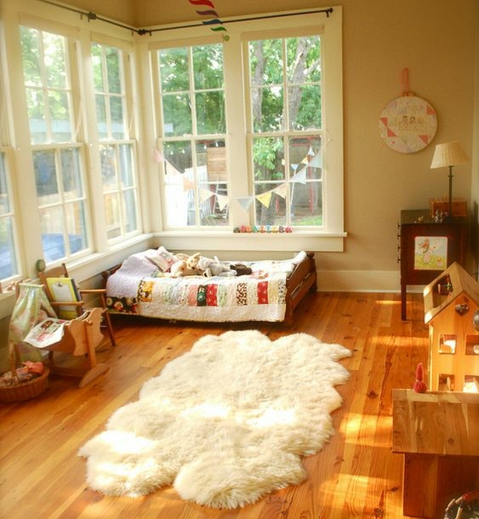 parquet en bois, tapis blanc, lit bébé montessori au sol, petite chaise, maisonnettes en bois, mur couleur beige, méthode montessori
